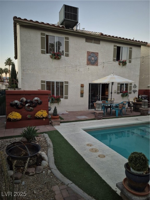 Rear view of property with an outdoor fire pit, a tiled roof, a patio area, and stucco siding