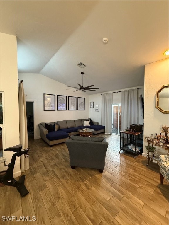 Living room featuring light wood finished floors, lofted ceiling, a ceiling fan, and arched walkways