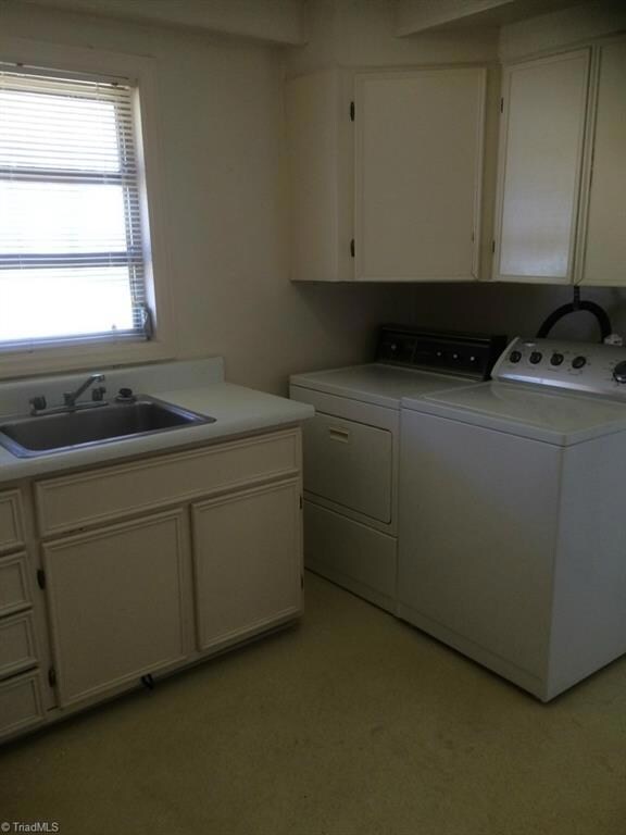 Laundry room with washer and dryer, sink and abundant cabinets.