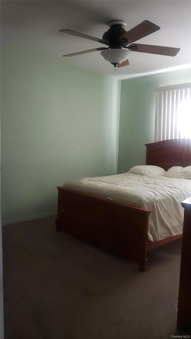 Bedroom with ceiling fan and dark colored carpet