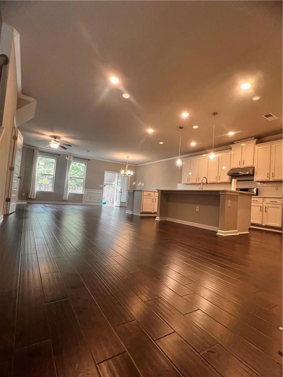 Unfurnished living room with a chandelier, a sink, dark wood-type flooring, ceiling fan, and recessed lighting