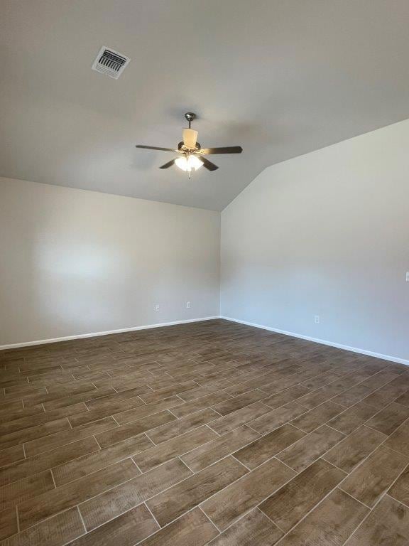 Empty room with dark wood-style flooring, lofted ceiling, and ceiling fan