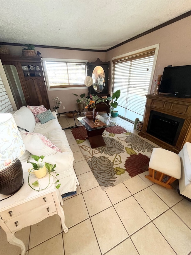 Living area with crown molding, light tile patterned floors, plenty of natural light, a fireplace, and a textured ceiling