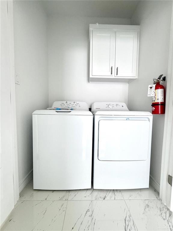 Laundry room featuring light marble finish flooring, cabinet space, and washer and clothes dryer