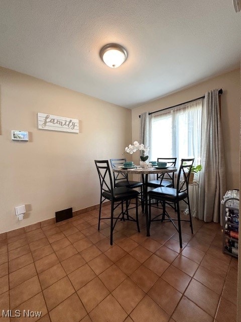 Tiled dining area featuring a textured ceiling