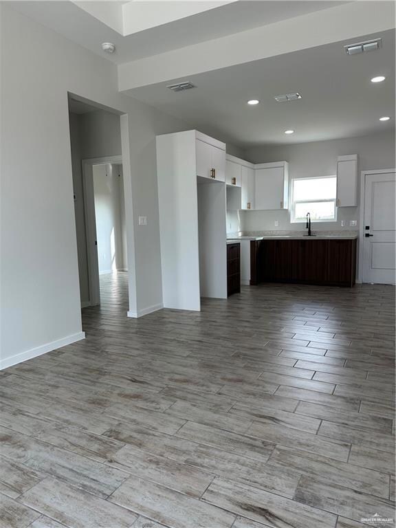 Kitchen featuring sink, light wood-type flooring, dark brown cabinets, and white cabinets