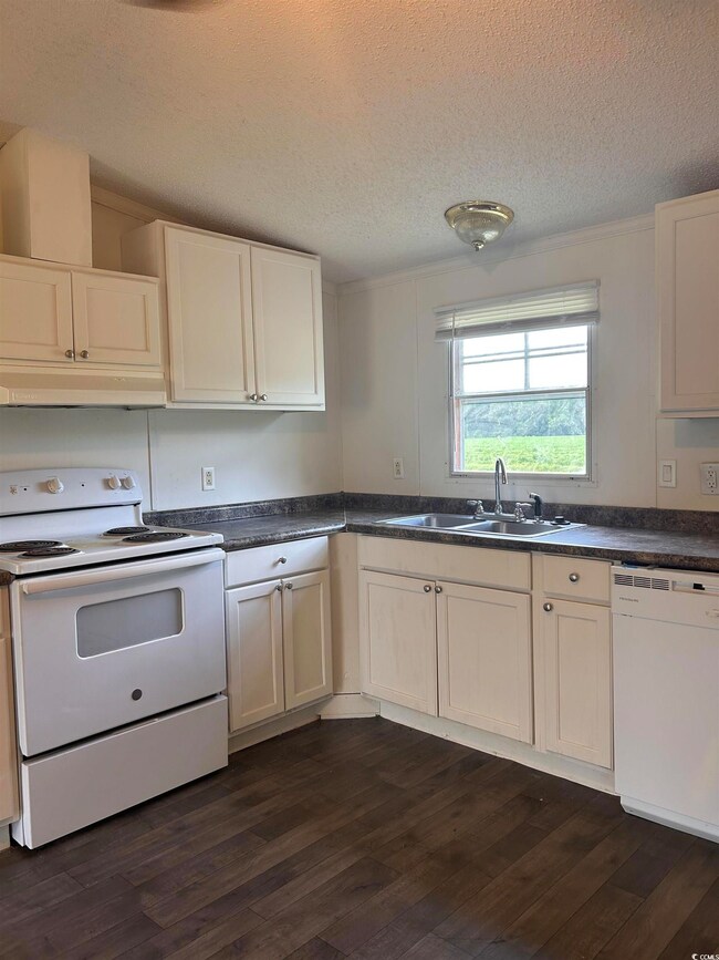 Kitchen with sink, white appliances, dark hardwood