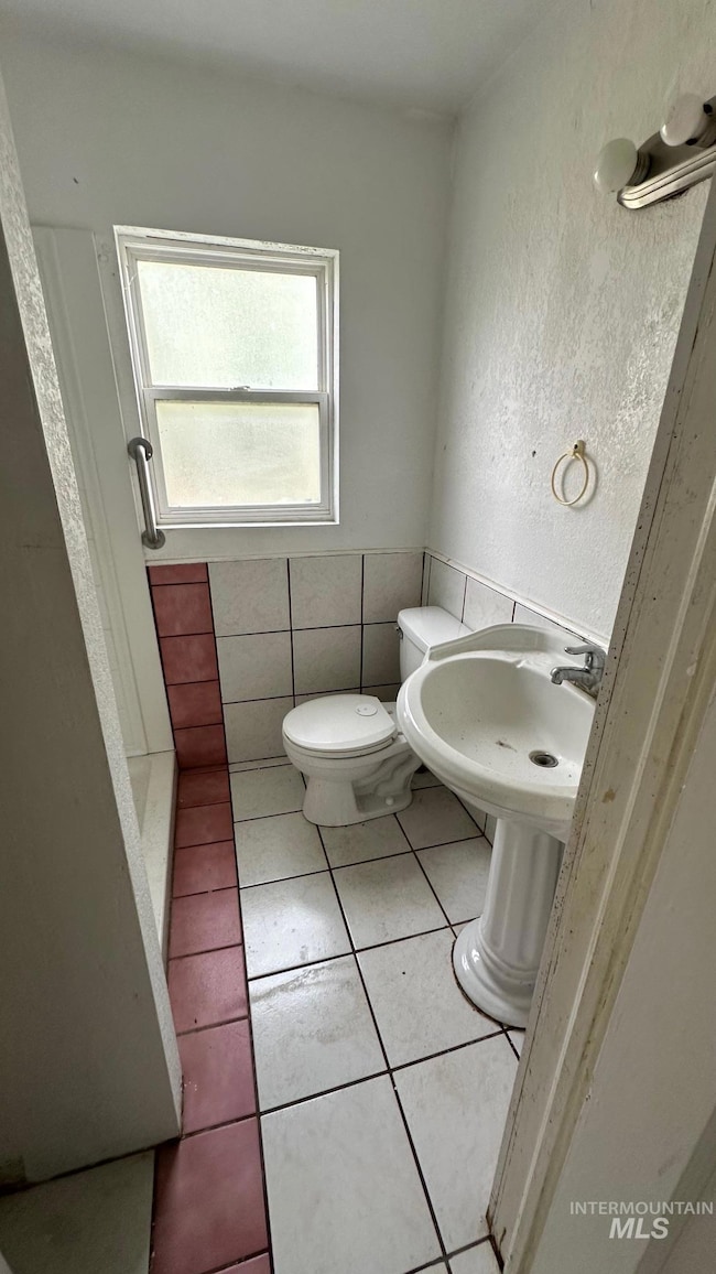 Bathroom featuring light tile patterned floors, a textured wall, tile walls, and a stall shower