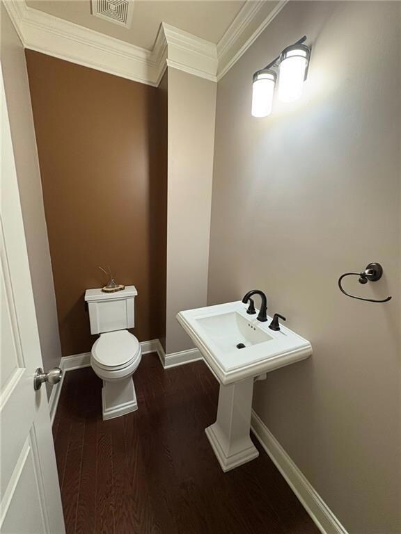 Half bath featuring ornamental molding and wood finished floors