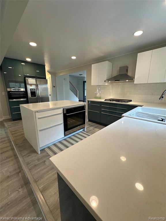 Kitchen featuring white cabinets, decorative backsplash, light stone counters, a kitchen island, and recessed lighting