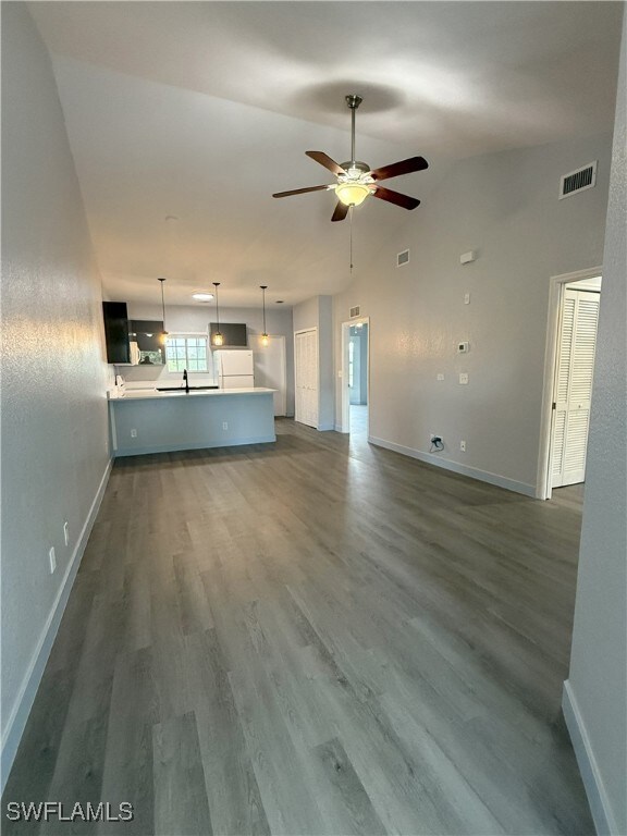 Unfurnished living room featuring a ceiling fan, b