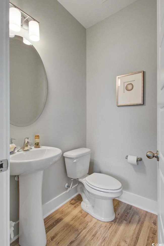Bathroom featuring a sink, toilet, wood finished f