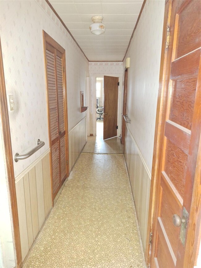 Corridor with crown molding and wooden walls