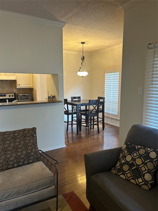 Living area with crown molding, dark wood-style flooring, and a textured ceiling