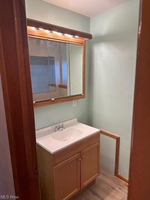 Bathroom with light hardwood floors, mirror, and v