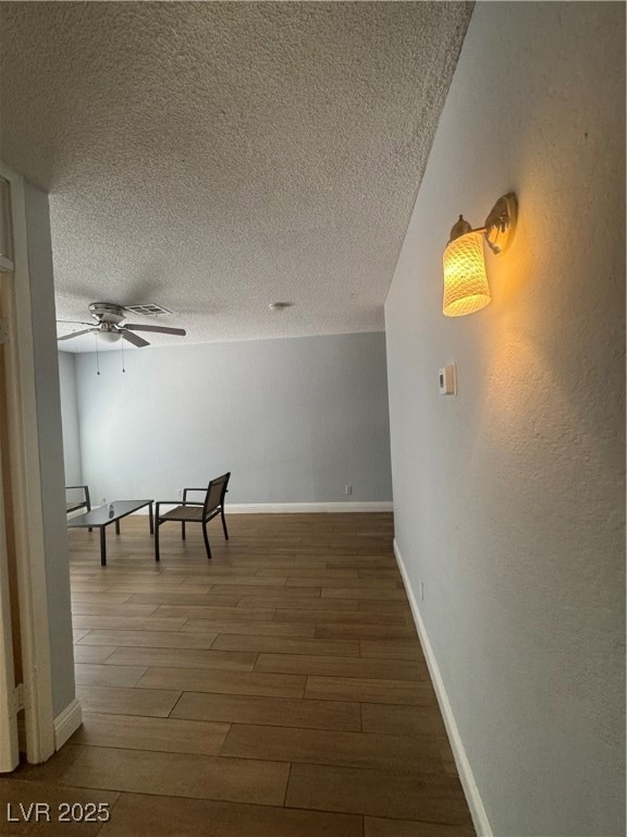 Hallway featuring baseboards, a textured ceiling,