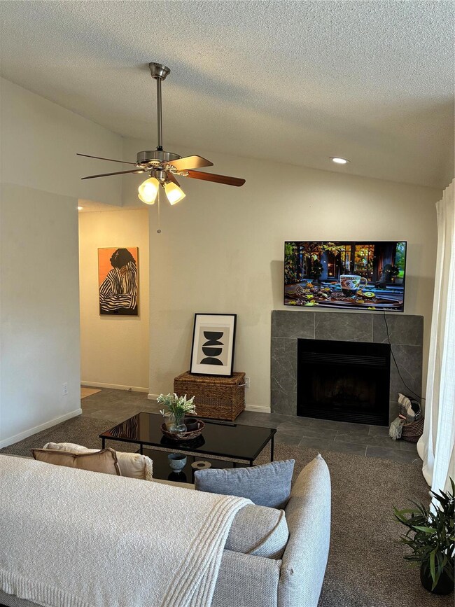 Carpeted living area with a ceiling fan, vaulted c