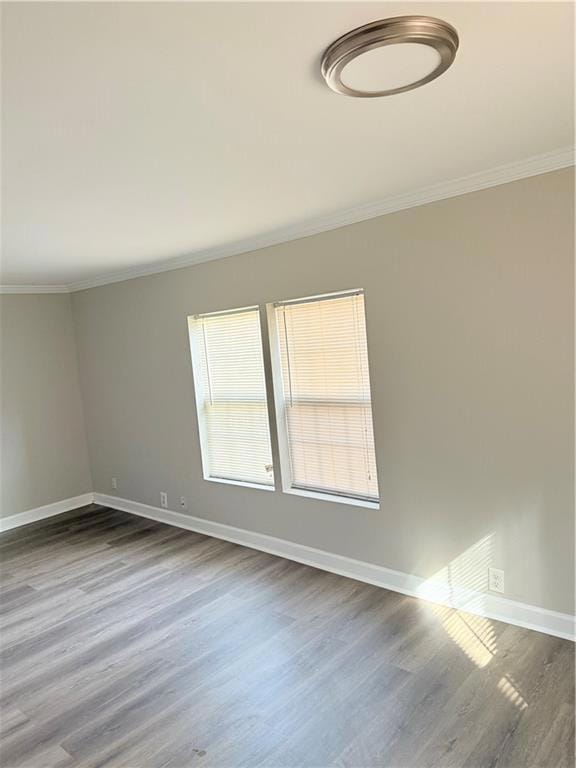Empty room with crown molding, baseboards, and woo