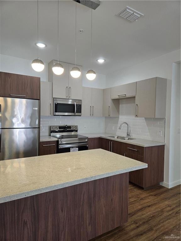 Kitchen with a sink, fridge, dark wood-style floors, range, and visible vents