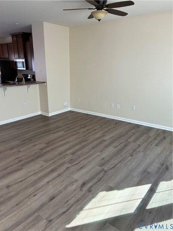 Unfurnished living room with dark wood finished floors and ceiling fan
