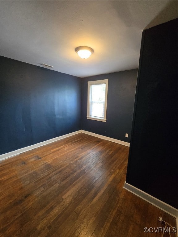 Spare room with dark wood-style flooring and baseb