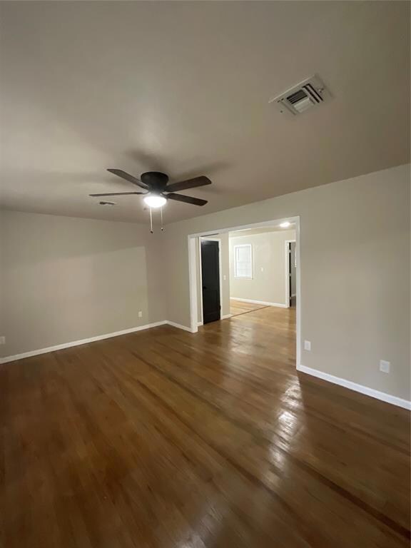 Unfurnished room featuring ceiling fan and dark wood-type flooring