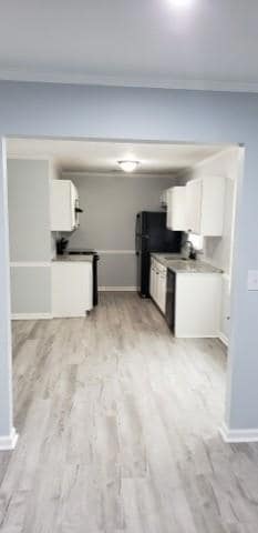 Kitchen with white cabinets, ornamental molding, light wood finished floors, black appliances, and light stone countertops