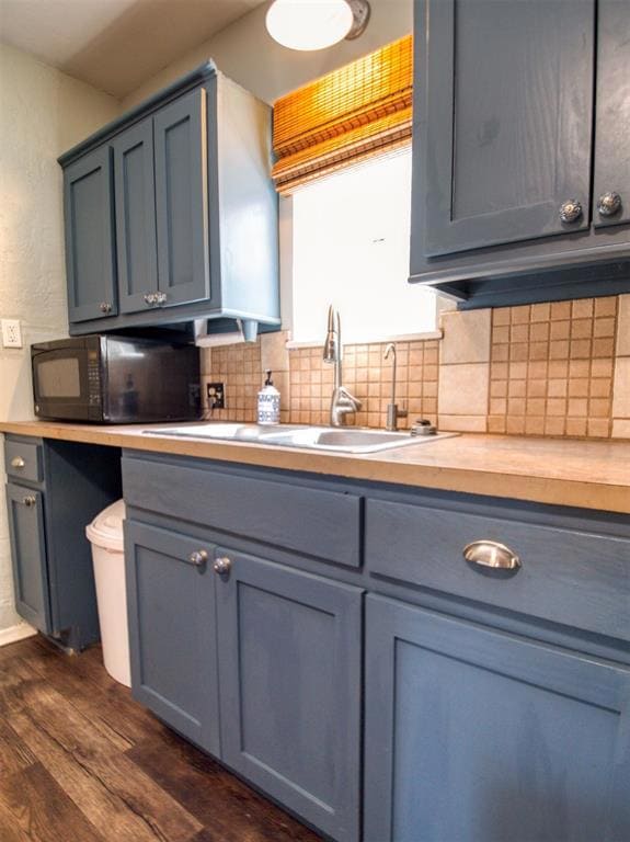 Kitchen with black microwave, a sink, dark wood-style flooring, tasteful backsplash, and gray cabinetry