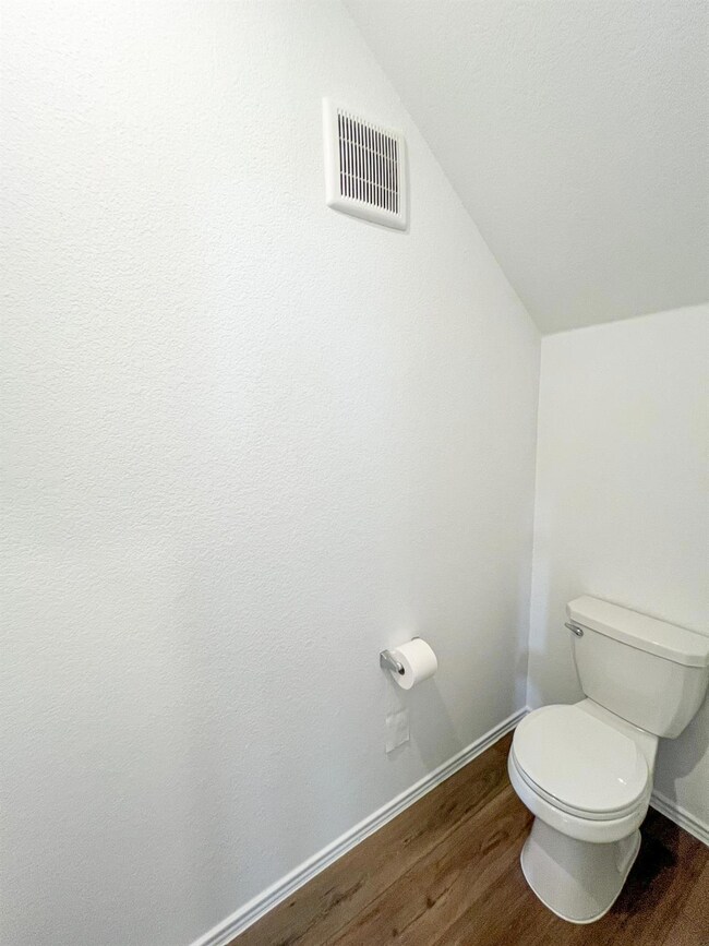 Bathroom with dark wood-style flooring and vaulted ceiling