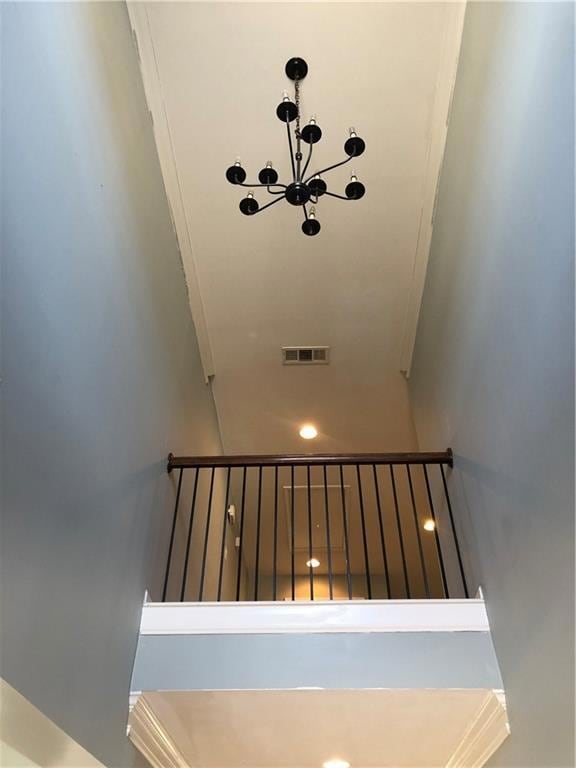 Stairs featuring visible vents and an inviting chandelier