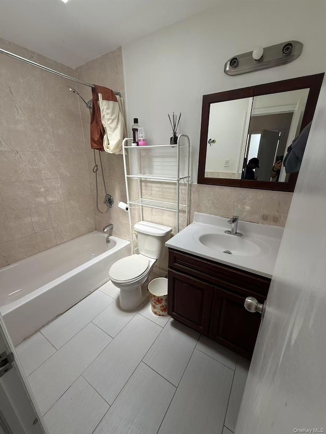 Bathroom featuring bathtub / shower combination, vanity, tile walls, and light tile patterned floors