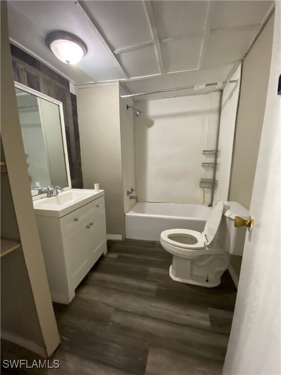Full bath with shower / washtub combination, toilet, vanity, and wood finished floors