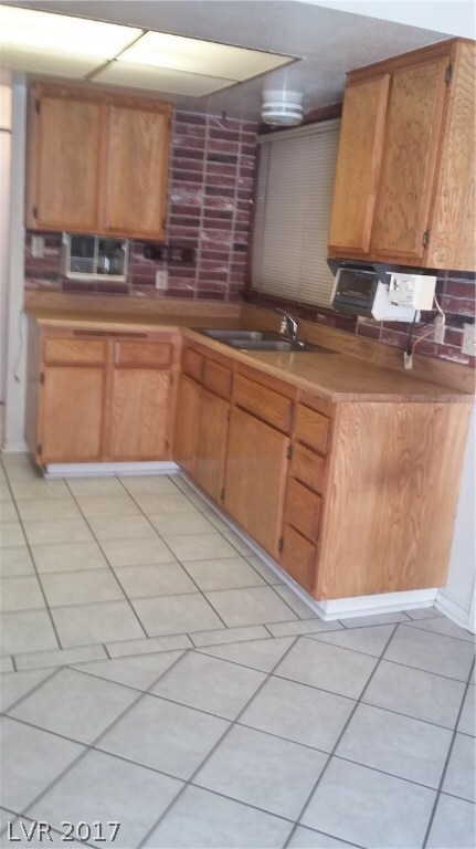 Kitchen has wood cabinetry window above sink and a