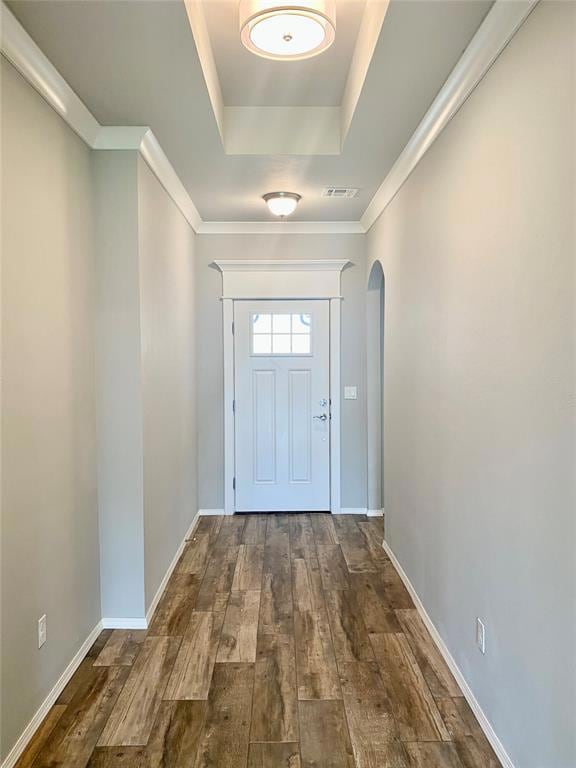 Doorway to outside featuring arched walkways, dark wood-style flooring, a raised ceiling, and baseboards