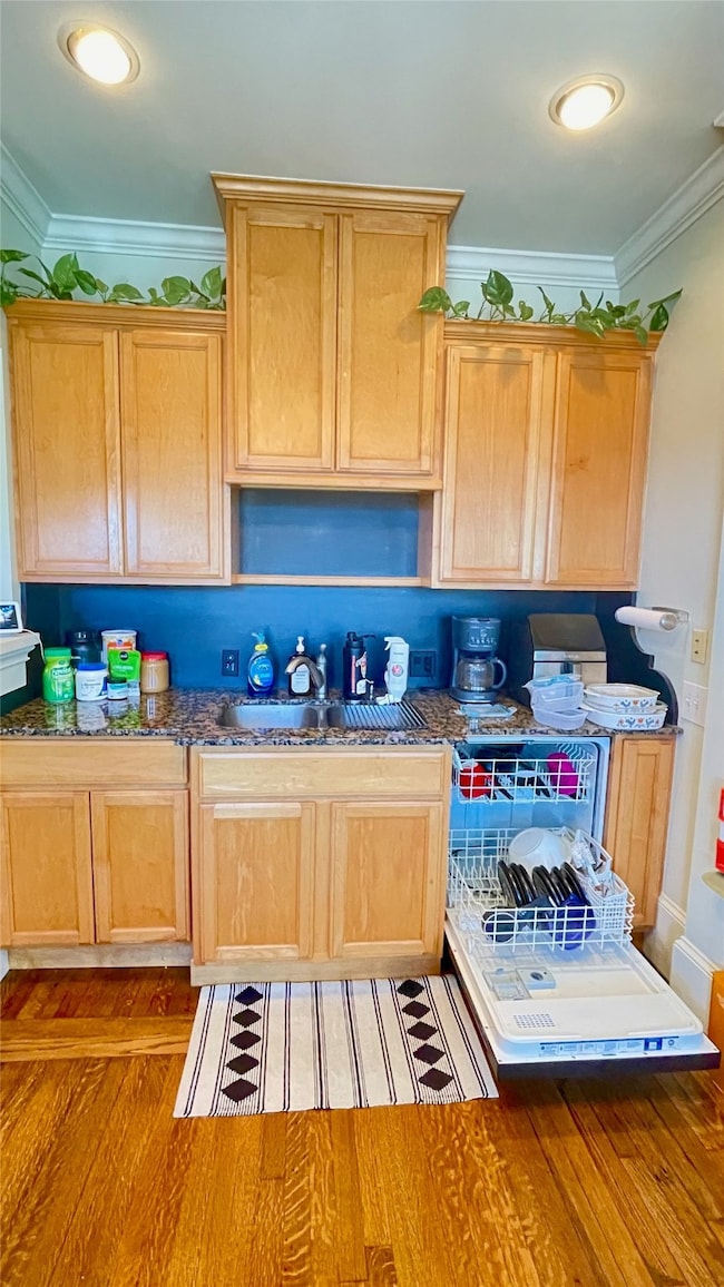 Light-soaked kitchen featuring double sink, dishwasher and original oak flooring.