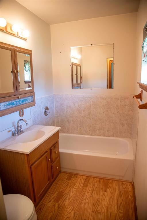 Bathroom featuring toilet, a tub to relax in, vani