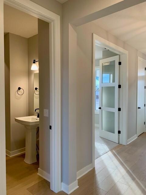 Powder room off foyer features pedestal sink.