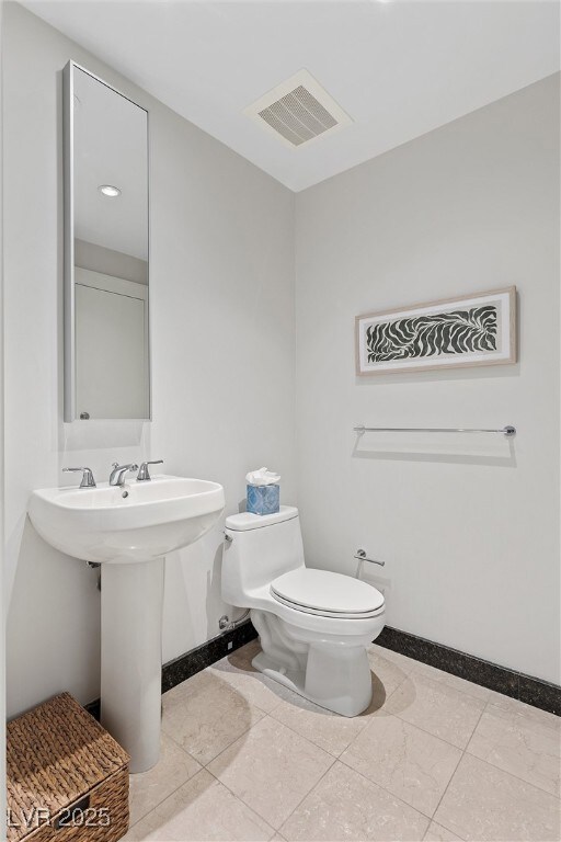 Half bathroom with toilet, baseboards, and visible