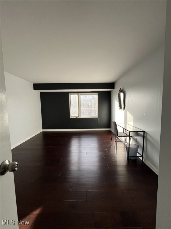Spare room featuring dark wood-type flooring