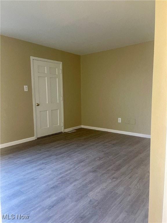 Empty room featuring dark wood finished floors and baseboards