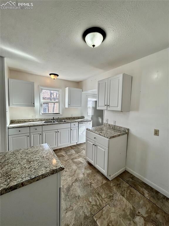 Kitchen featuring white cabinets, dark stone count