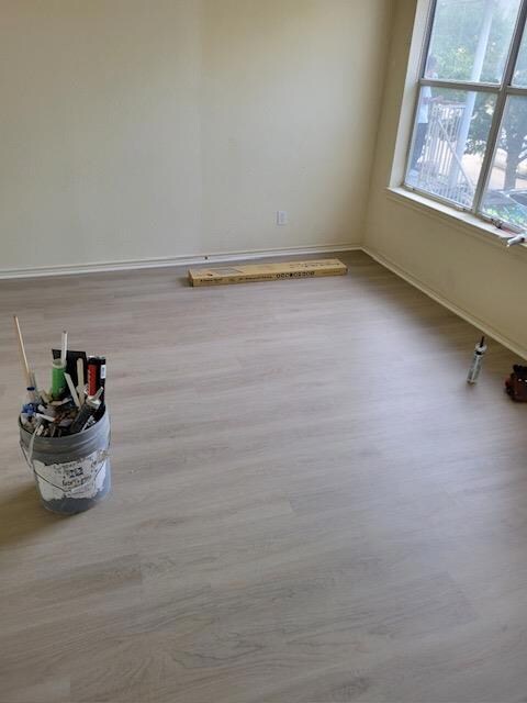 Unfurnished room featuring baseboards and wood fi