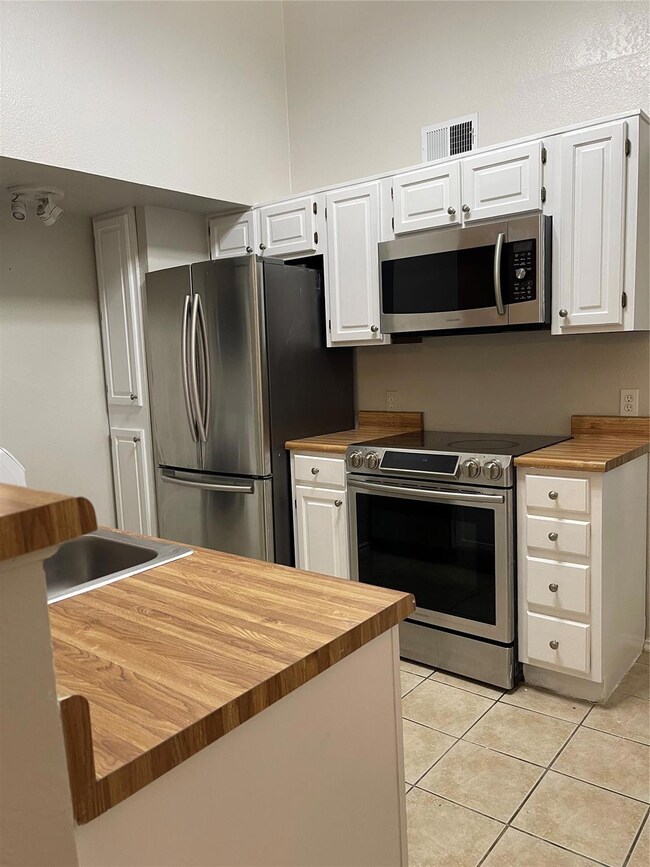 Kitchen featuring butcher block counters, white ca