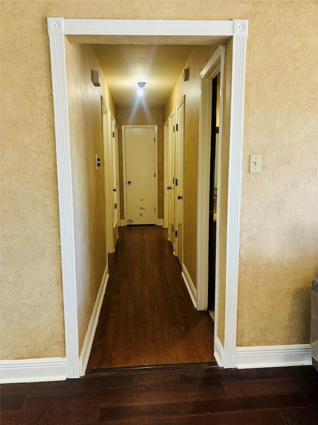 Hall with dark wood-style floors and a textured wall