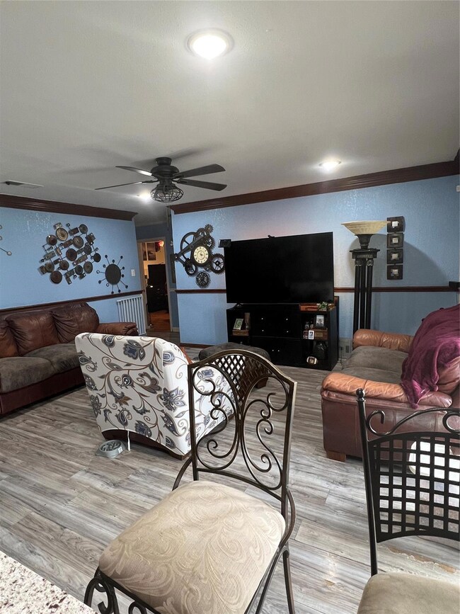 Living room with ornamental molding, a ceiling fan