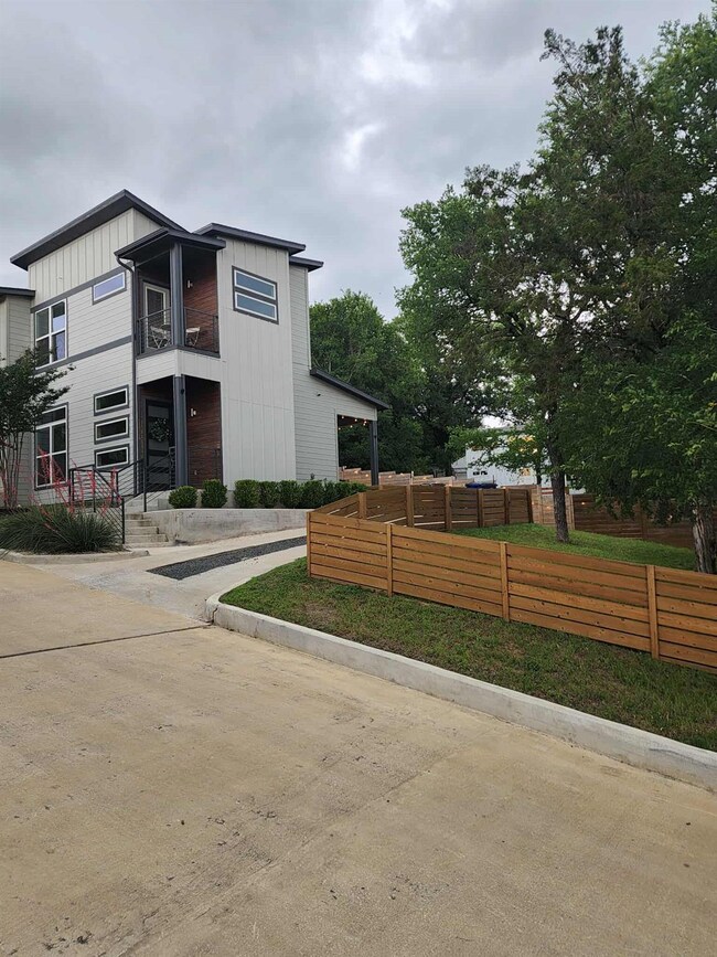 View of side of home with fence, a balcony, and b