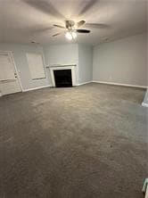 Unfurnished living room featuring ceiling fan, a fireplace, and carpet