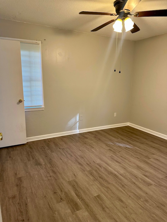 Unfurnished room featuring wood finished floors, a ceiling fan, and baseboards
