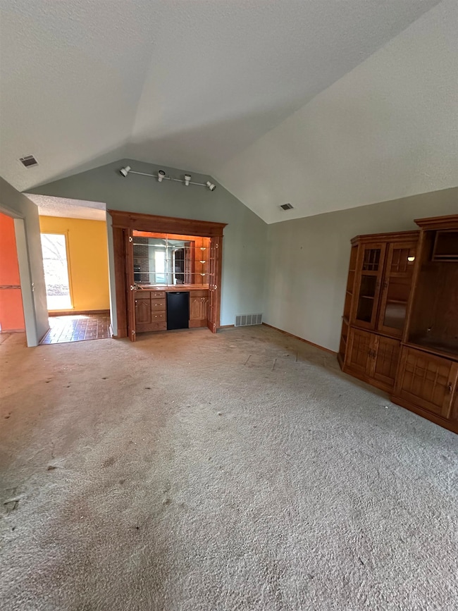 Unfurnished living room with lofted ceiling, a tex