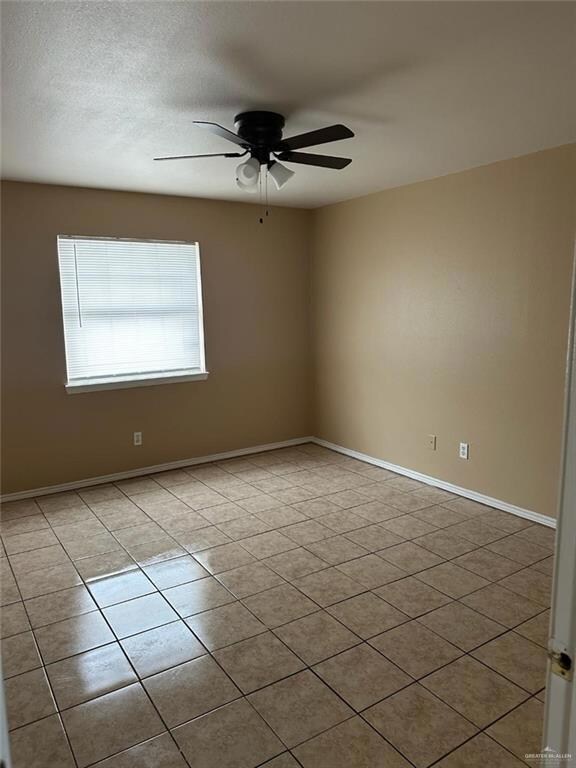 Tiled spare room featuring ceiling fan and a textured ceiling
